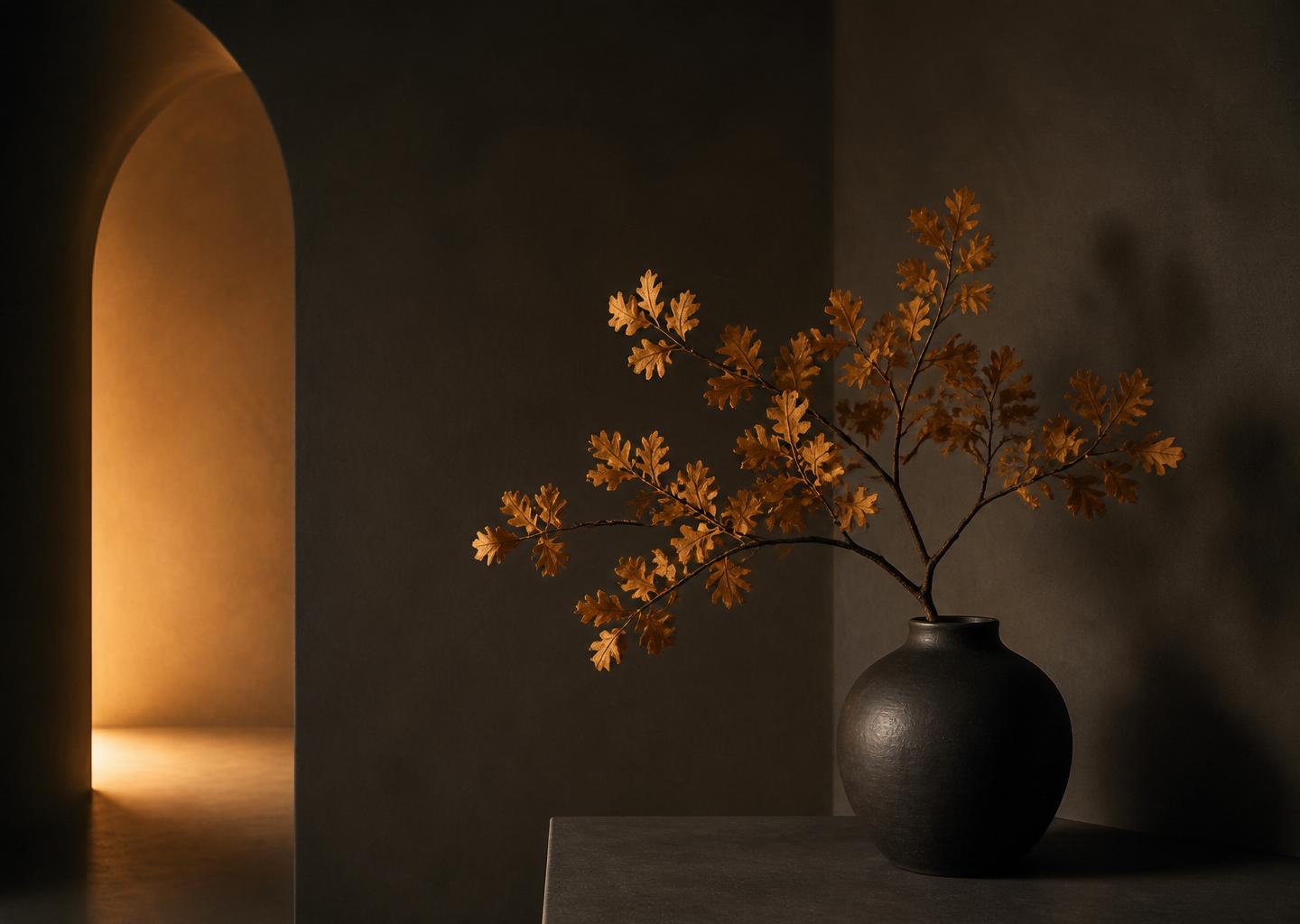 A minimalist dark interior with warm amber light and an oak branch, reflecting the OG Management brand.